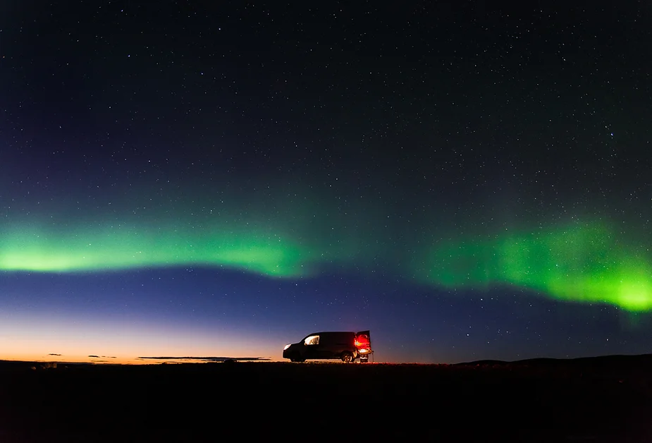 ¿Cuándo deberías viajar a Islandia? Una camper permanece estacionada en un paraje islandés desértico durante el espectáculo de las auroras boreales en mitad de la noche.