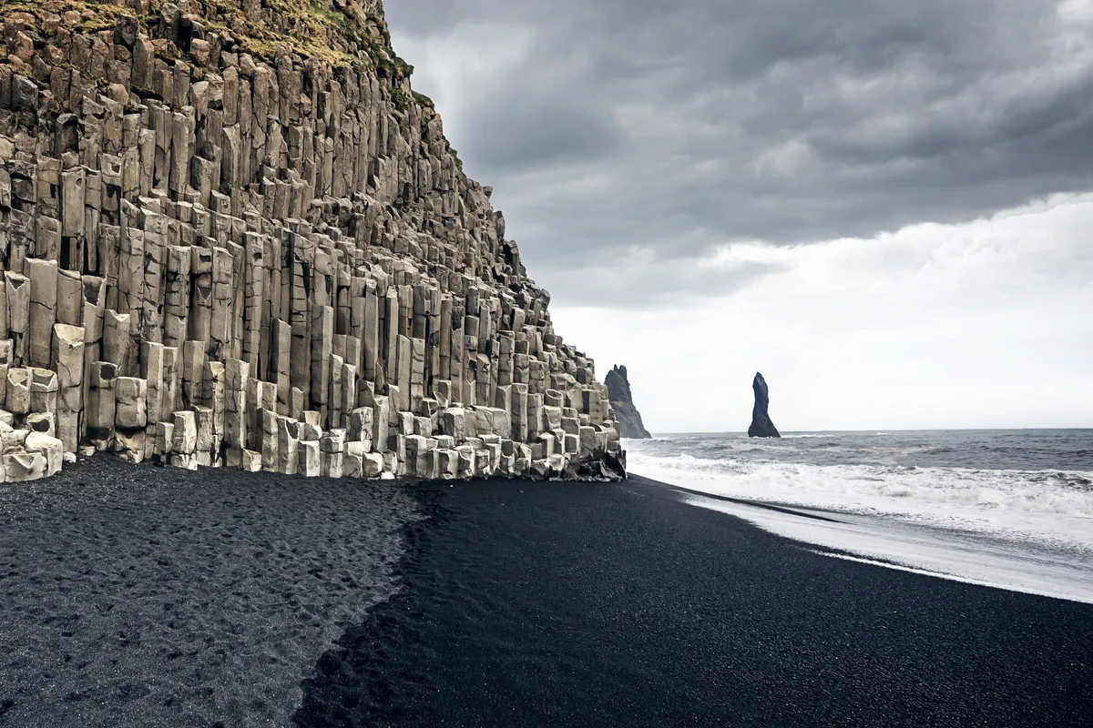 Vista panorámica de las impresionantes playas de arena negra de Islandia, en contraste con las espectaculares olas y los escarpados acantilados costeros