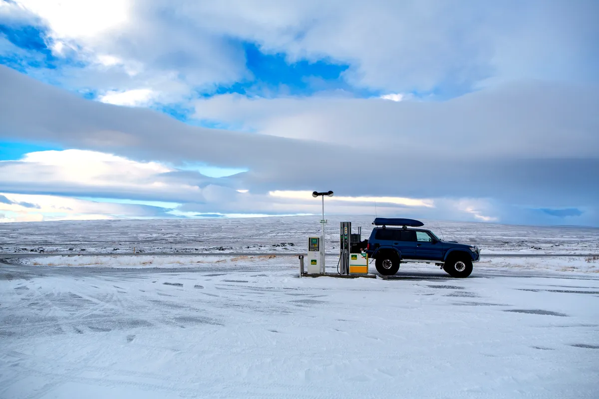 Repostaje de veh&iacute;culos 4x4 en una gasolinera en el paisaje nevado de Islandia, que resalta las condiciones remotas de un viaje por carretera en invierno.