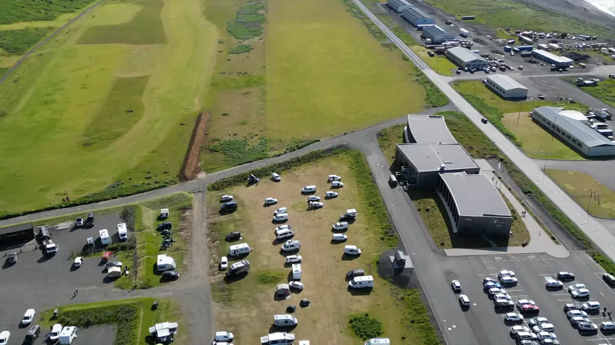 Camping en Islandia con varias autocaravanas estacionadas en un área designada, rodeado de naturaleza y estructuras modernas. Elegir campings adecuados es clave para un viaje cómodo y sin preocupaciones en camper.