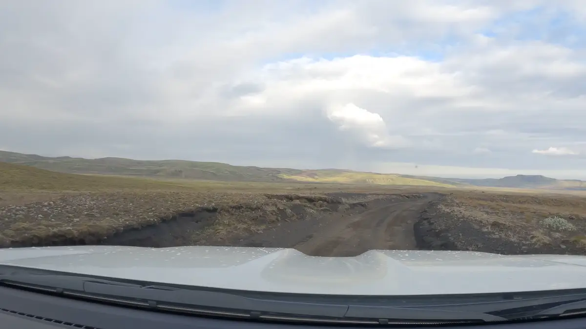 Vista desde el parabrisas de una autocaravana recorriendo una carretera de grava en las Tierras Altas de Islandia. Las rutas F requieren un vehículo 4x4 para explorar estos paisajes remotos con seguridad.
