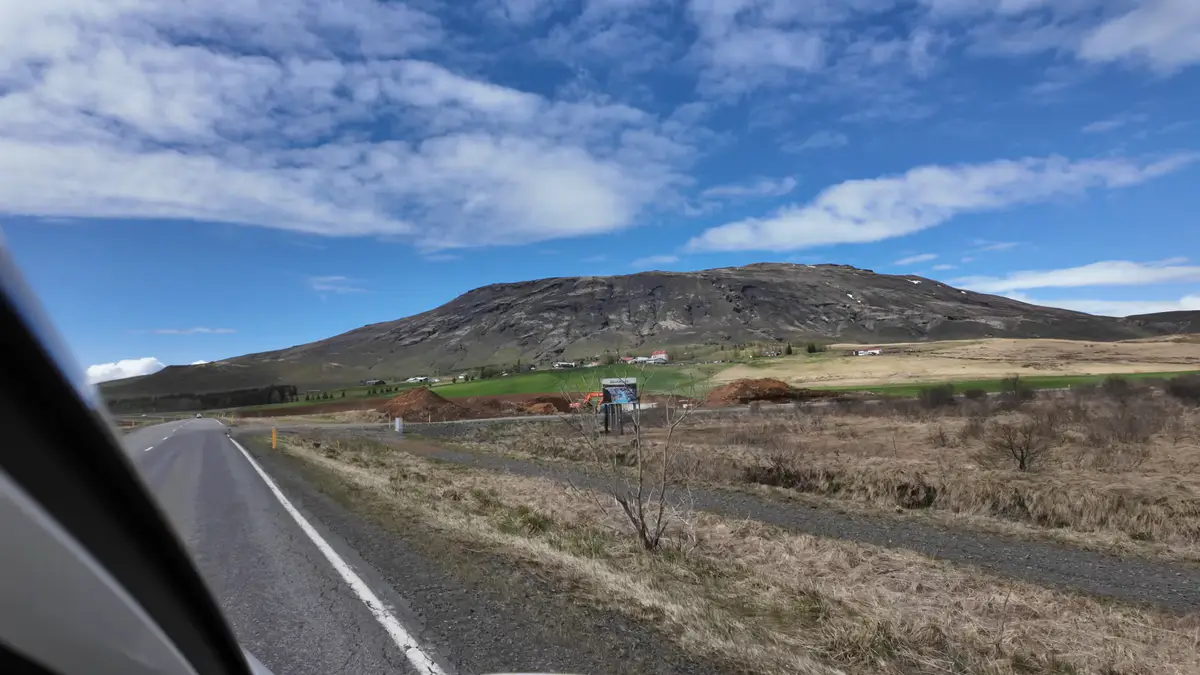 Vista desde una autocaravana recorriendo una carretera en Islandia, con montañas y paisajes rurales en el horizonte. Un road trip en camper permite disfrutar de la naturaleza sin prisas.