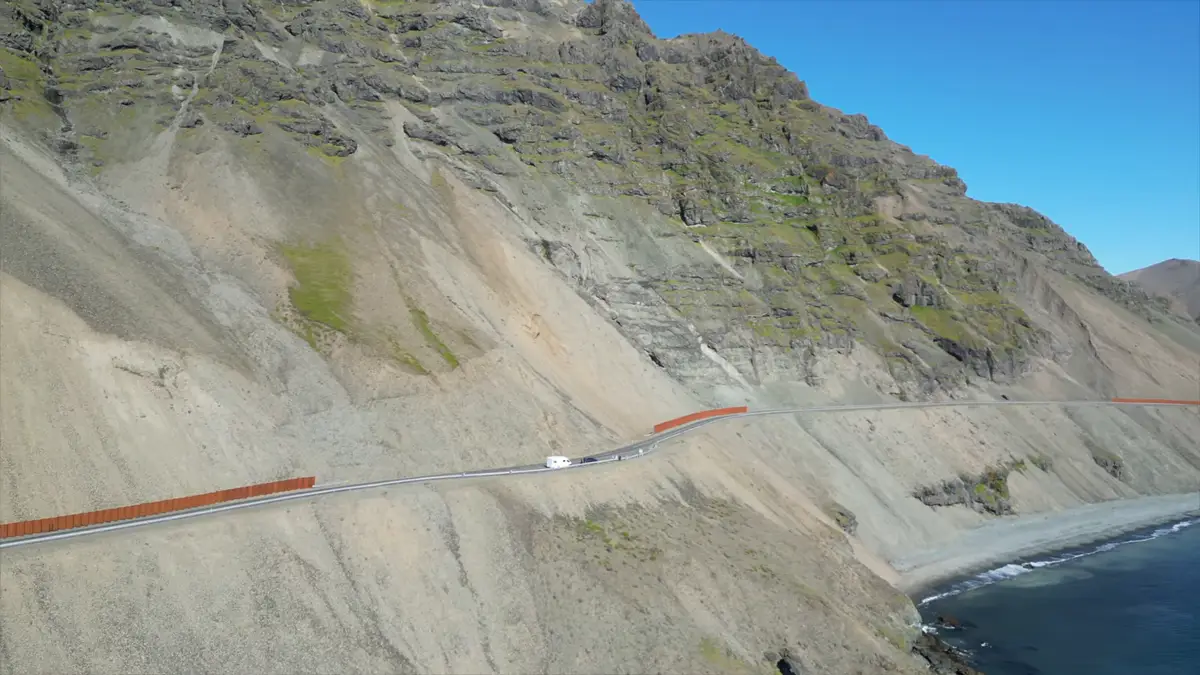 Autocaravana recorriendo una carretera escénica junto a un acantilado en Islandia, con vistas al océano y montañas escarpadas. Viajar en camper permite descubrir paisajes impresionantes lejos de las rutas convencionales.