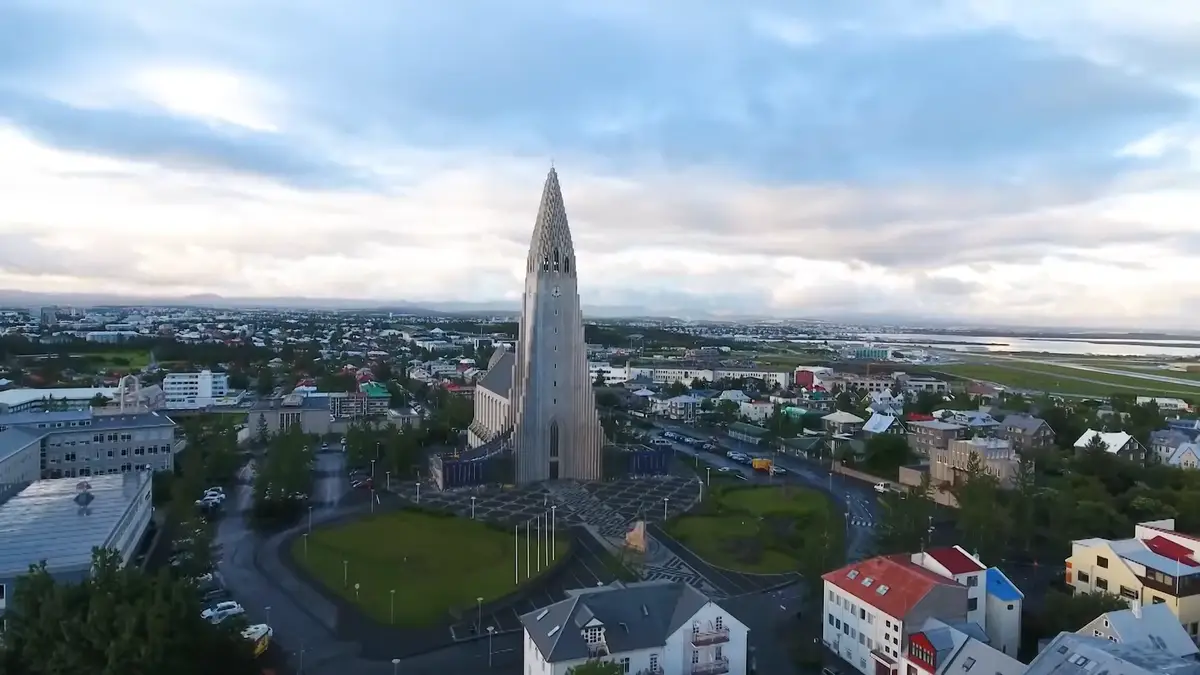 Vista aérea de Hallgrímskirkja, la icónica iglesia de Reikiavik, con la ciudad y el aeropuerto en el fondo. Un punto de partida imprescindible para un viaje en autocaravana por Islandia.
