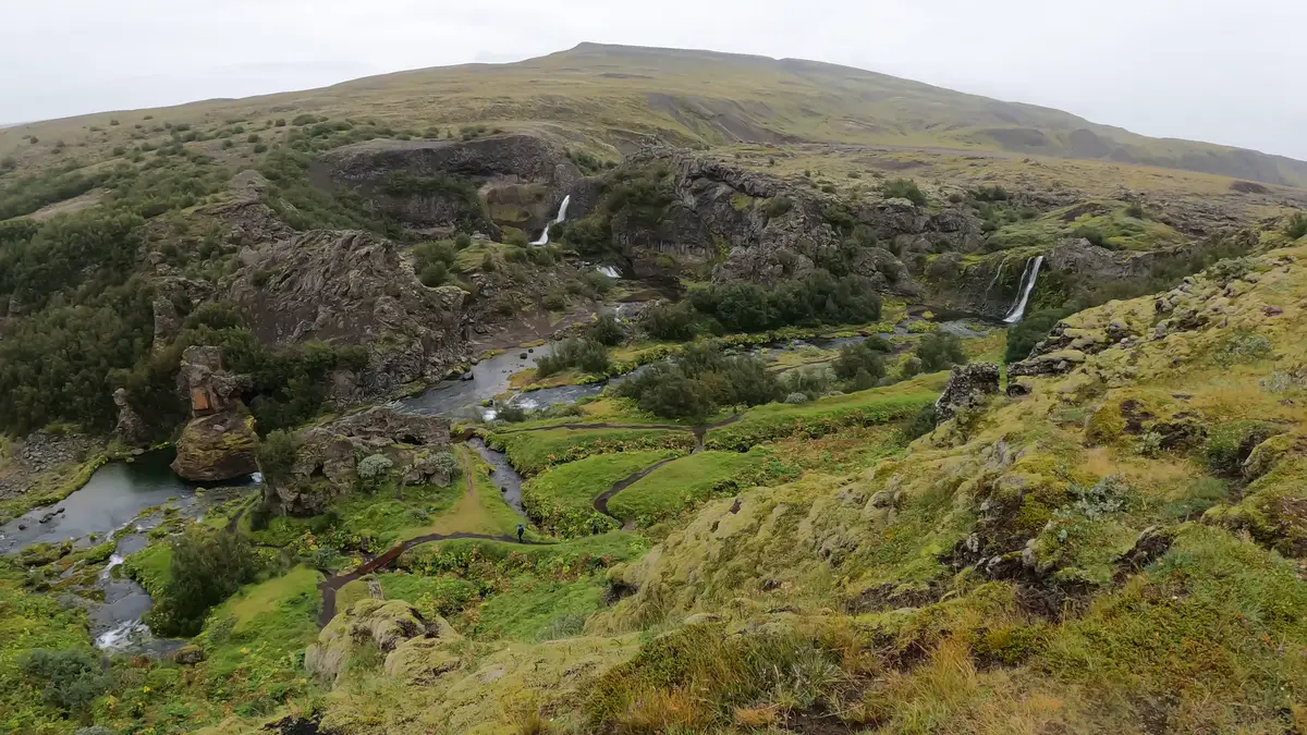 Vista panorámica del valle de Gjáin en Islandia, con cascadas, ríos y senderos serpenteantes rodeados de vegetación. Un destino oculto ideal para explorar en un viaje en autocaravana.