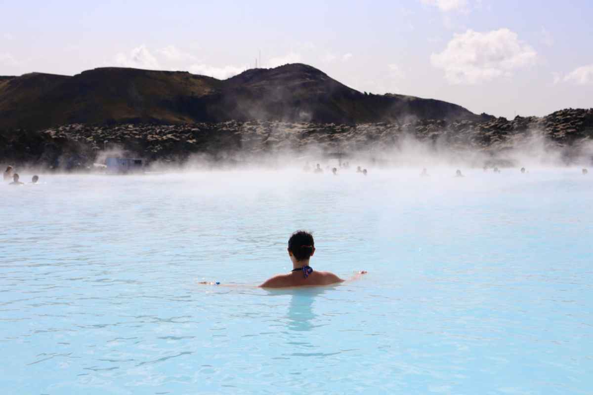 Blue Lagoon en Islandia Una mujer con el pelo recogido se relaja nadando en la Blue Lagoon de Islandia en un día soleado.
