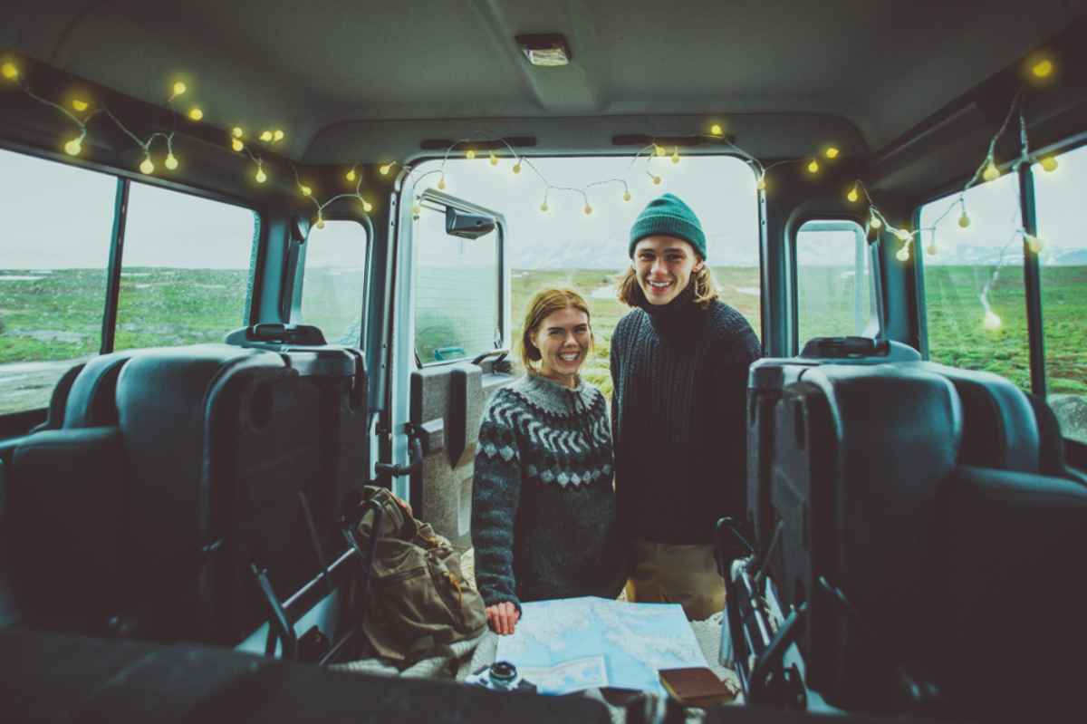 Una pareja de ni&ntilde;o y ni&ntilde;a mira con alegr&iacute;a mientras consulta un mapa de Islandia con toda la informaci&oacute;n sobre las carreteras del pa&iacute;s.