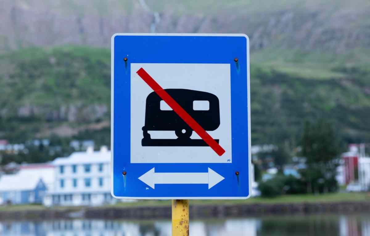 Primer plano de una se&ntilde;al de tr&aacute;fico en Islandia con el icono de una autocaravana tachada con una franja roja, simbolizando la prohibici&oacute;n de acampar en la zona.