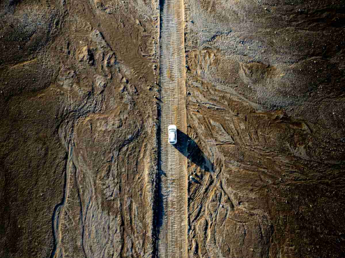 Vehículo blanco rodeado de rocas Vehículo blanco conduciendo por una carretera islandesa rodeado de piedras.
