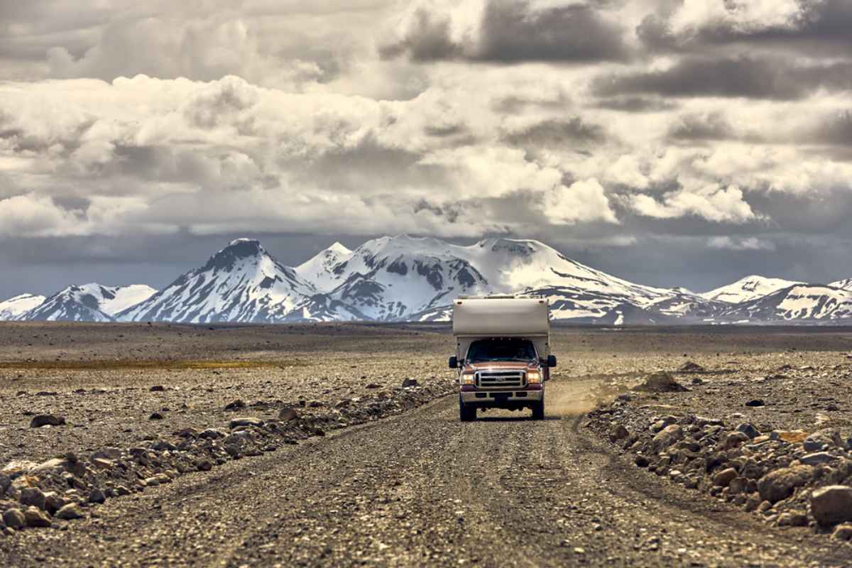 Autocaravana 4x4 conduciendo por una carretera islandesa Autocaravana 4x4 conduciendo por una carretera islandesa con grandes montañas al fondo