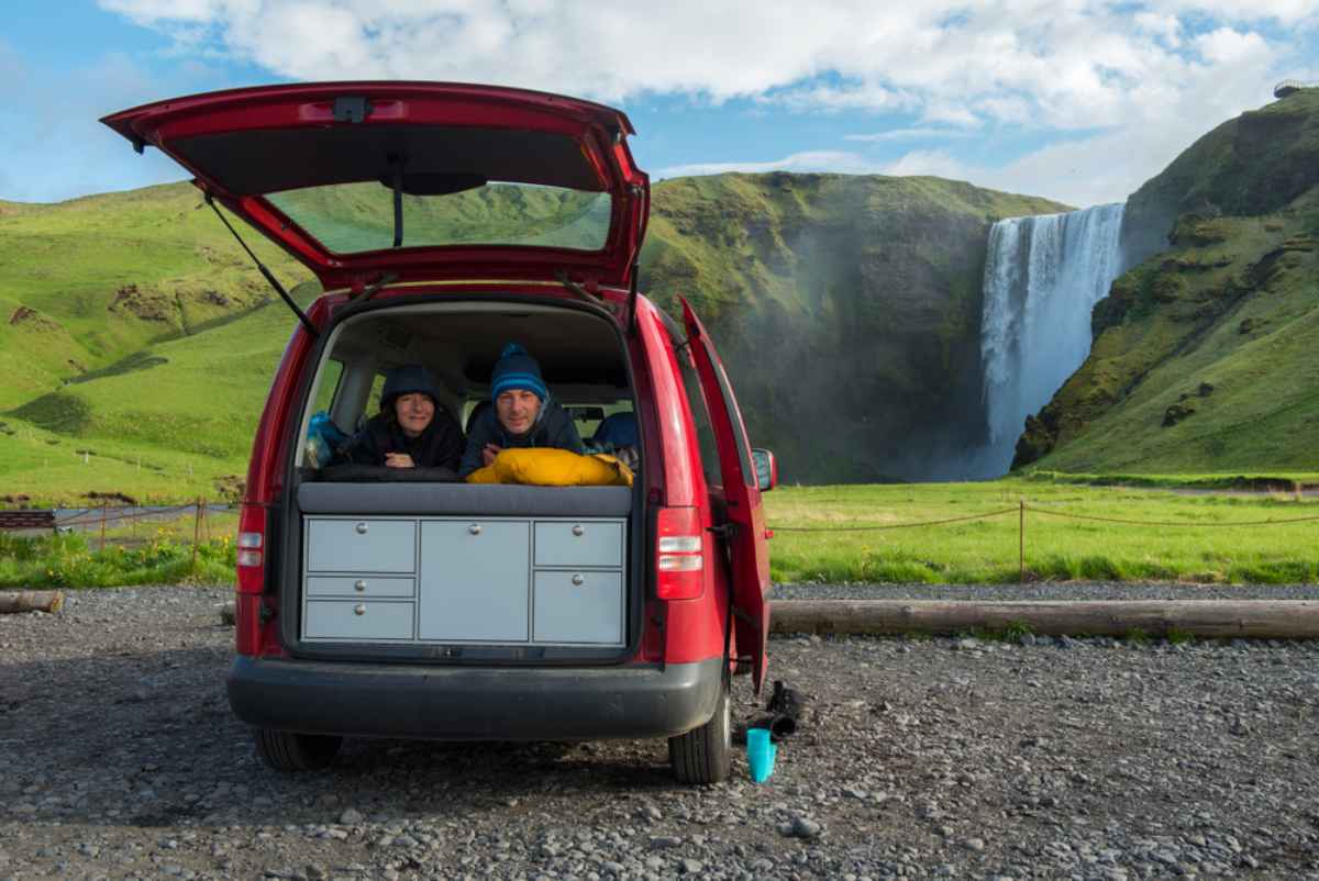 Una pareja de excursionistas disfruta las vistas de una cascada Una pareja de excursionistas disfruta las hermosas vistas de una cascada en Islandia desde su autocaravana.