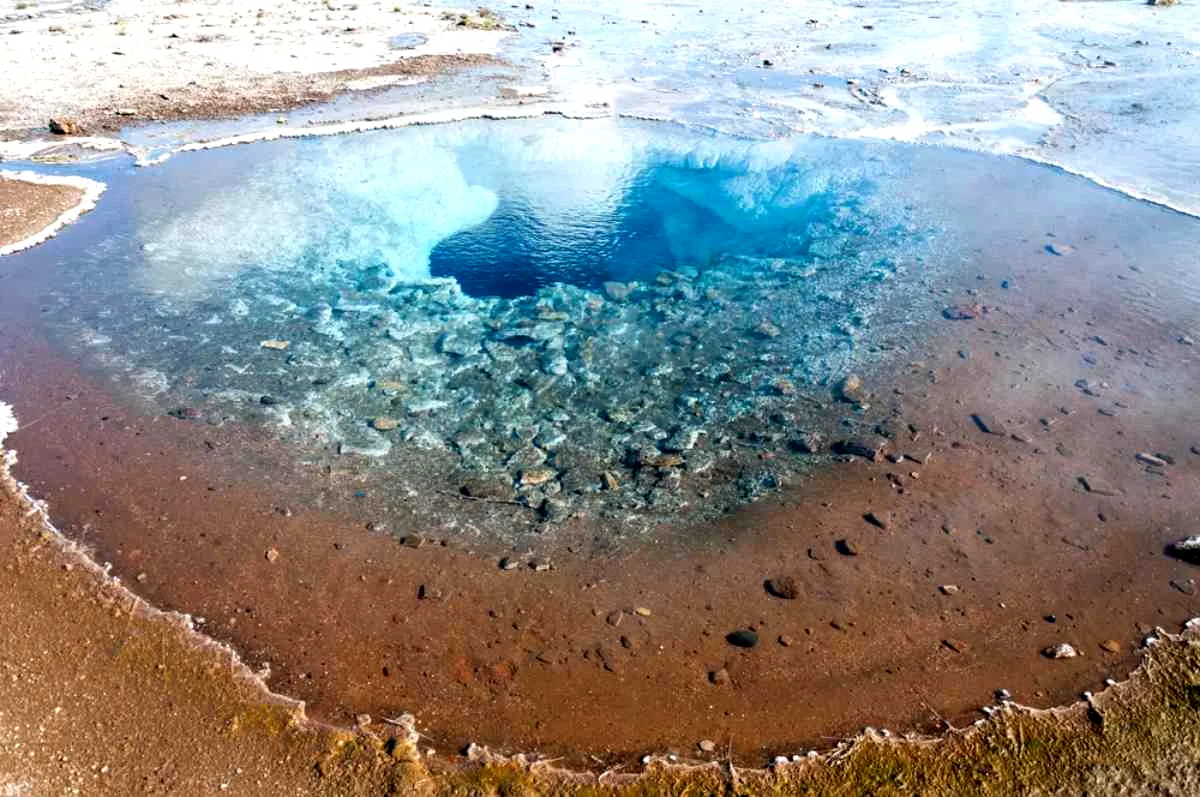 Poza geotermal de agua azul turquesa en la Secret Lagoon, borde mineral.