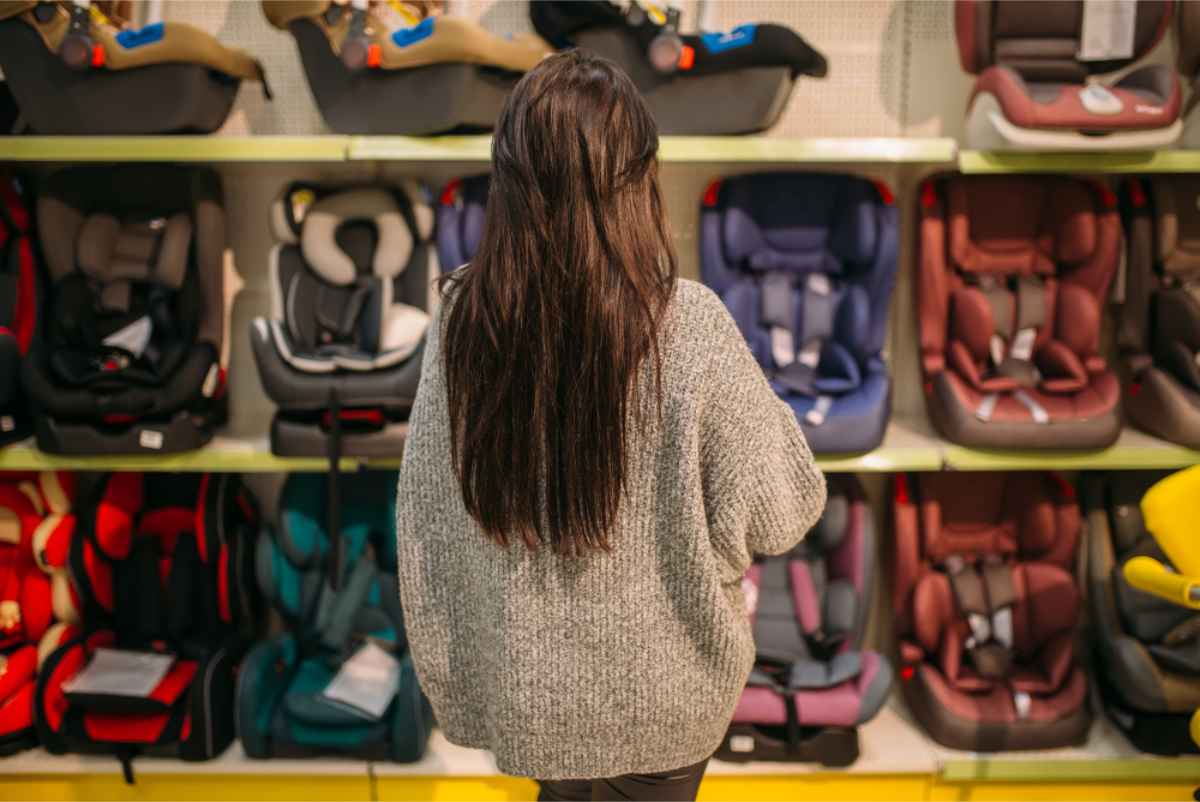 Mujer delante de varias sillas infantiles en una tienda