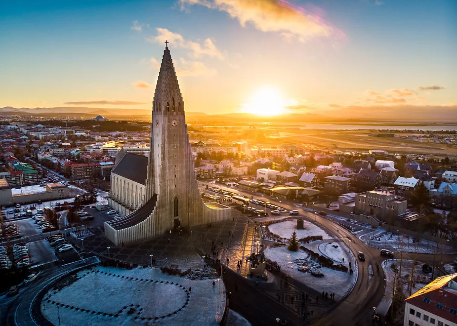 Vista de dron de la ciudad de Reikiavik durante el atardecer en lo que parece un día invernal por la nieve que rodea a la iglesia Hallgrímskirkja.