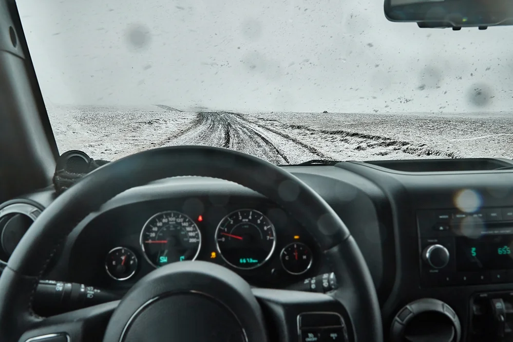Vista desde el interior de un coche conduciendo por una carretera cubierta de nieve en Islandia